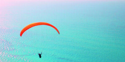 Paraglider soaring over the sea